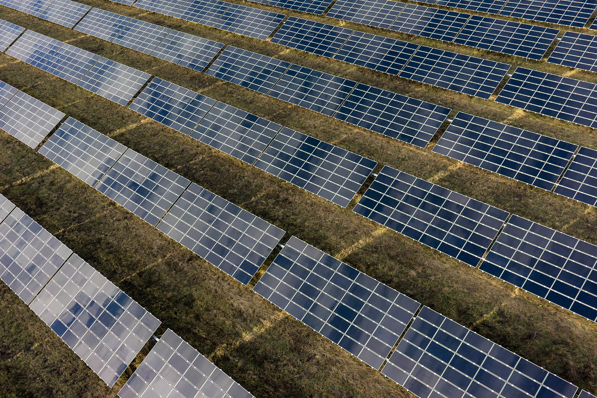 Luftaufnahme eines Solarparks mit Modulfeldern in Reihenstruktur